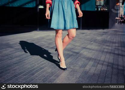 A young woman in retro shoes is walking on the street on a sunny day