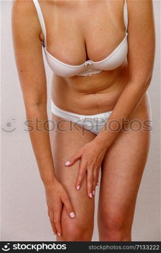 a young woman in white underwear leans forward and holds her leg. on white isolated background