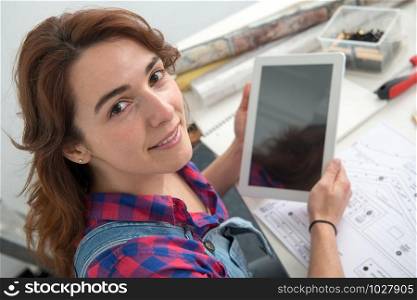 a young woman interior designer sitting at desk using digital tablet