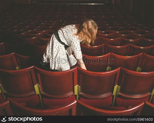 A young woman is about to take her seat in an empty auditorium
