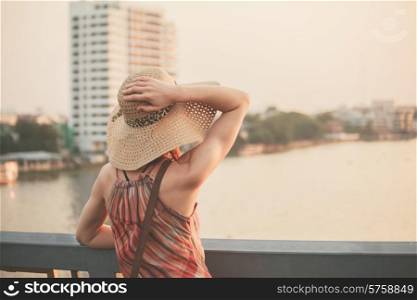 A young woman is admiring the sunset over the river in Bangkok, Thailand