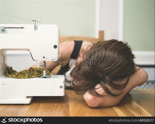 A young woman is asleep by her sewing machine
