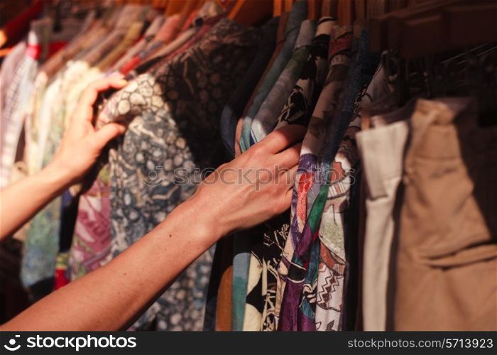 A young woman is browsing a rail of clothes at a street market