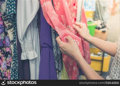 A young woman is browsing through clothing at a street market