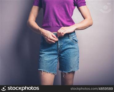 A young woman is closing the zip on her denim shorts