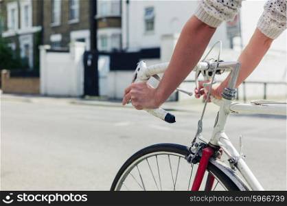 A young woman is cycling on the road in a city on a sunny day