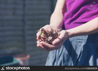 A young woman is doing gardening and i holding some weeds in her hands