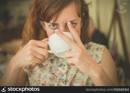 A young woman is drinking coffee and is displaying an obscene gesture with her fingers