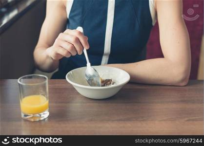 A young woman is eating breakfast and drinking orange juice by the window in a diner