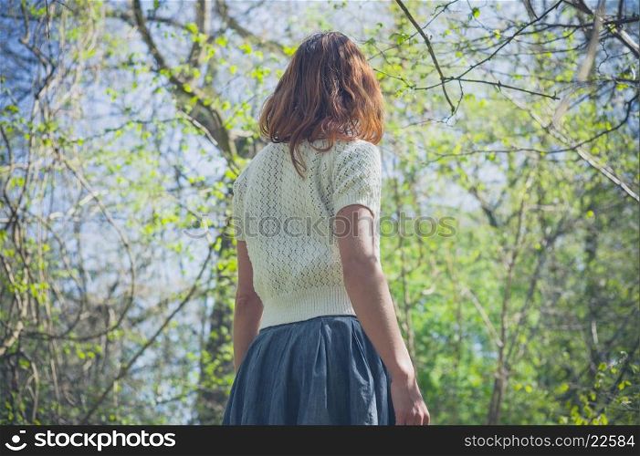 A young woman is exploring a forest on a sunny day