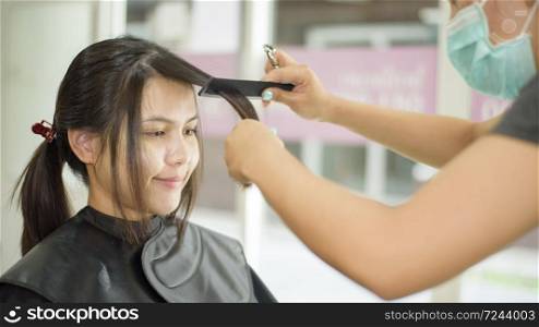 a young woman is getting a haircut in a hair salon , salon safety concept