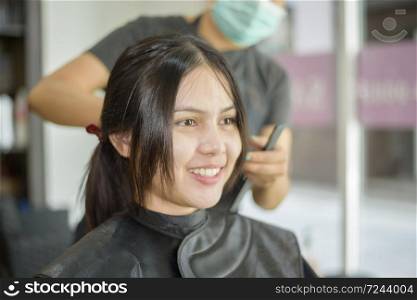 a young woman is getting a haircut in a hair salon , salon safety concept