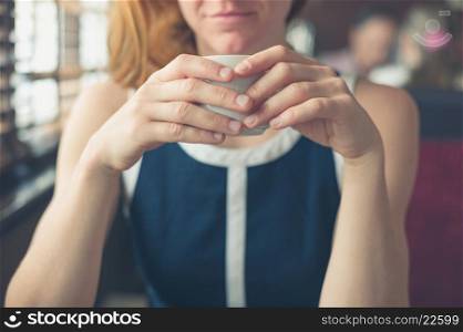 A young woman is having a cup of coffee by the window in a diner