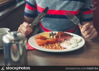 A young woman is having a traditional english breakfast in a diner