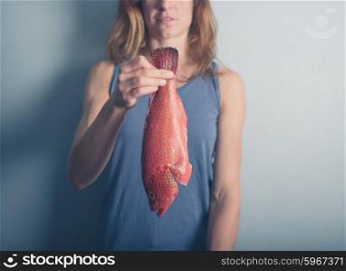 A young woman is holding a tropical red butterfish