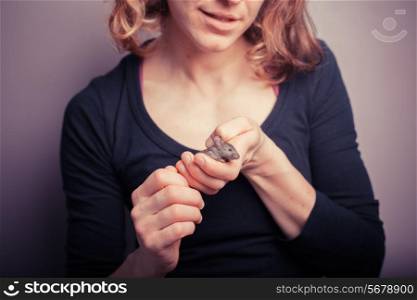 A young woman is holding her tiny pet mouse