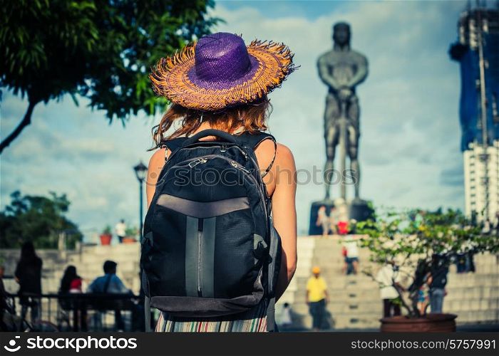 A young woman is looking at a statue in Manila