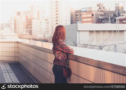 A young woman is looking at the skyline of city at sunset