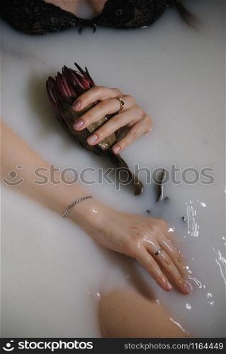 A young woman is lying in a bath filled with milk close up. A young woman is lying in a bath filled with milk.
