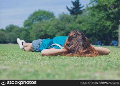 A young woman is lying in the grass and relaxing in a park on a summer day