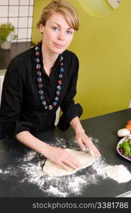 A young woman is making pizza dough on the kitchen counter at home in her apartment.