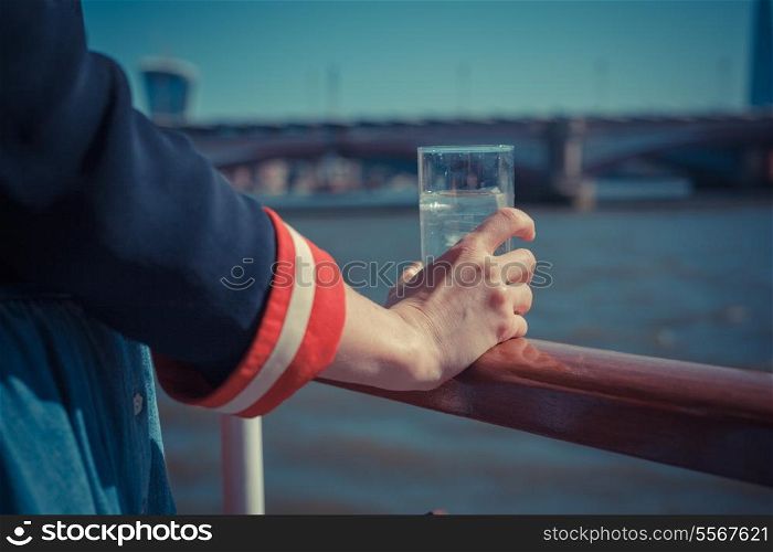 A young woman is on a boat and holding a glass of water