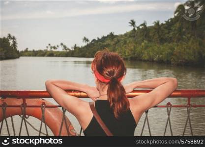 A young woman is on a boat and is cruising on a river in the jungle