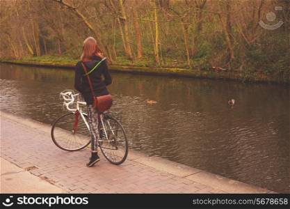 A young woman is on her bicycle by the canal