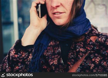 A young woman is on the phone outdoors in the street