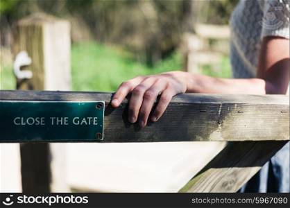 A young woman is opening a wooden gate in the forest