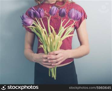 A young woman is posing with a bouquet of dead flowers