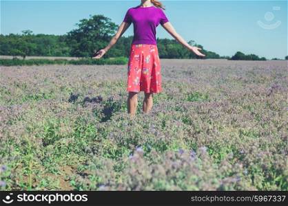A young woman is raising her arms in a field of purple flowers