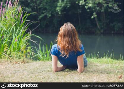 A young woman is relaxing by the water in a park on a summer day