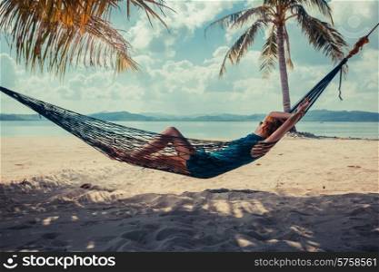 A young woman is relaxing in a hammock on a tropical beach