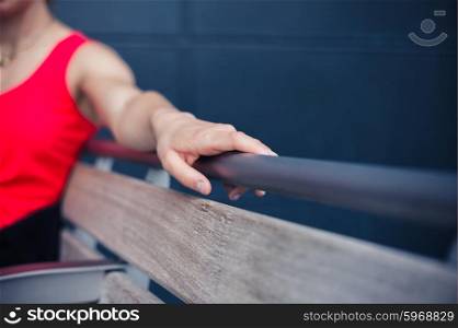 A young woman is resting on a bench outside on a sunny day