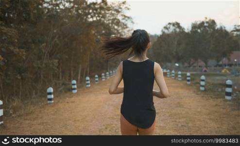 A young woman is running in nature outdoor at sunset