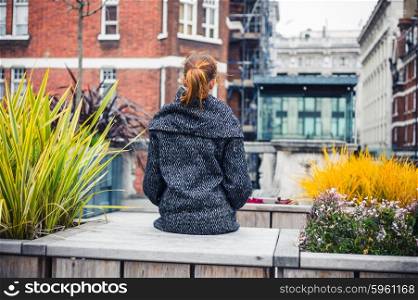 A young woman is sitting and relaxing on a bench in the city