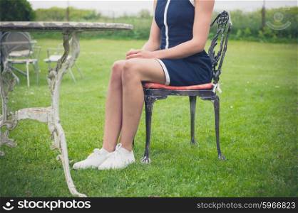 A young woman is sitting and relaxing on a chair on a lawn in a garden