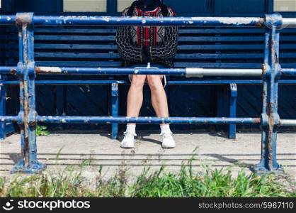 A young woman is sitting at a bus stop on the beach