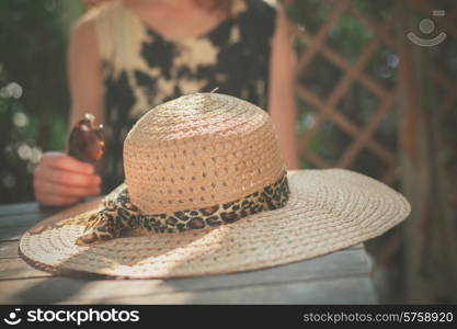 A young woman is sitting at a table with a big straw hat in front of her