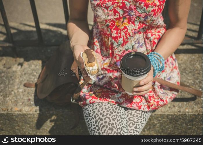 A young woman is sitting in the street with coffee and cake