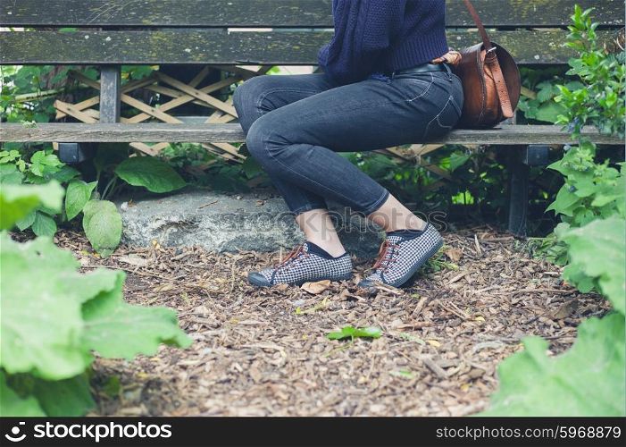 A young woman is sitting on a bench in a forest