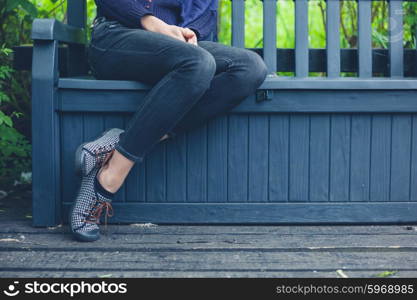 A young woman is sitting on a bench outside in nature