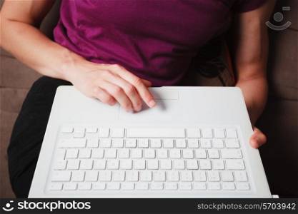 A young woman is sitting on a sofa and using a laptop computer