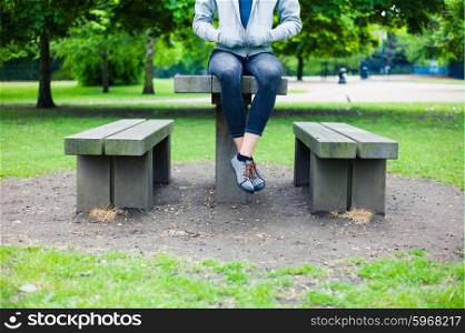 A young woman is sitting on a table in a park