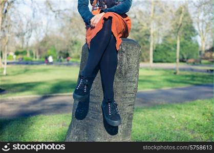 A young woman is sitting on a tree trunk