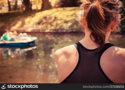 A young woman is sitting on the ground and relaxing by the water