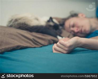 A young woman is sleeping in a bed with a cat next to her