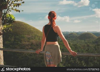 A young woman is standing and admiring the view of the famous Chocolate hills in Bohol, Philippines