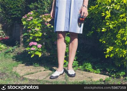 A young woman is standing and relaxing in a residential garden on a sunny summer day